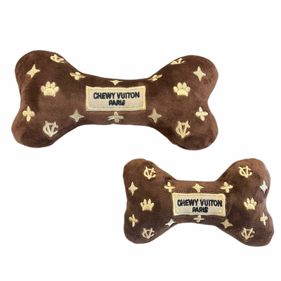 Plush brown dog bone toy with gold embroidered icons and a “Chewy Vutton Paris” label. Soft luxury squeaky chew toy for pets.