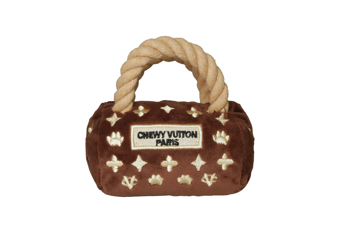 Plush luxury dog handbag toy in brown velvet with rope handles and embroidered gold icons, featuring a “Chewy Vutton Paris” label. Soft squeaky designer-style chew toy for pets.