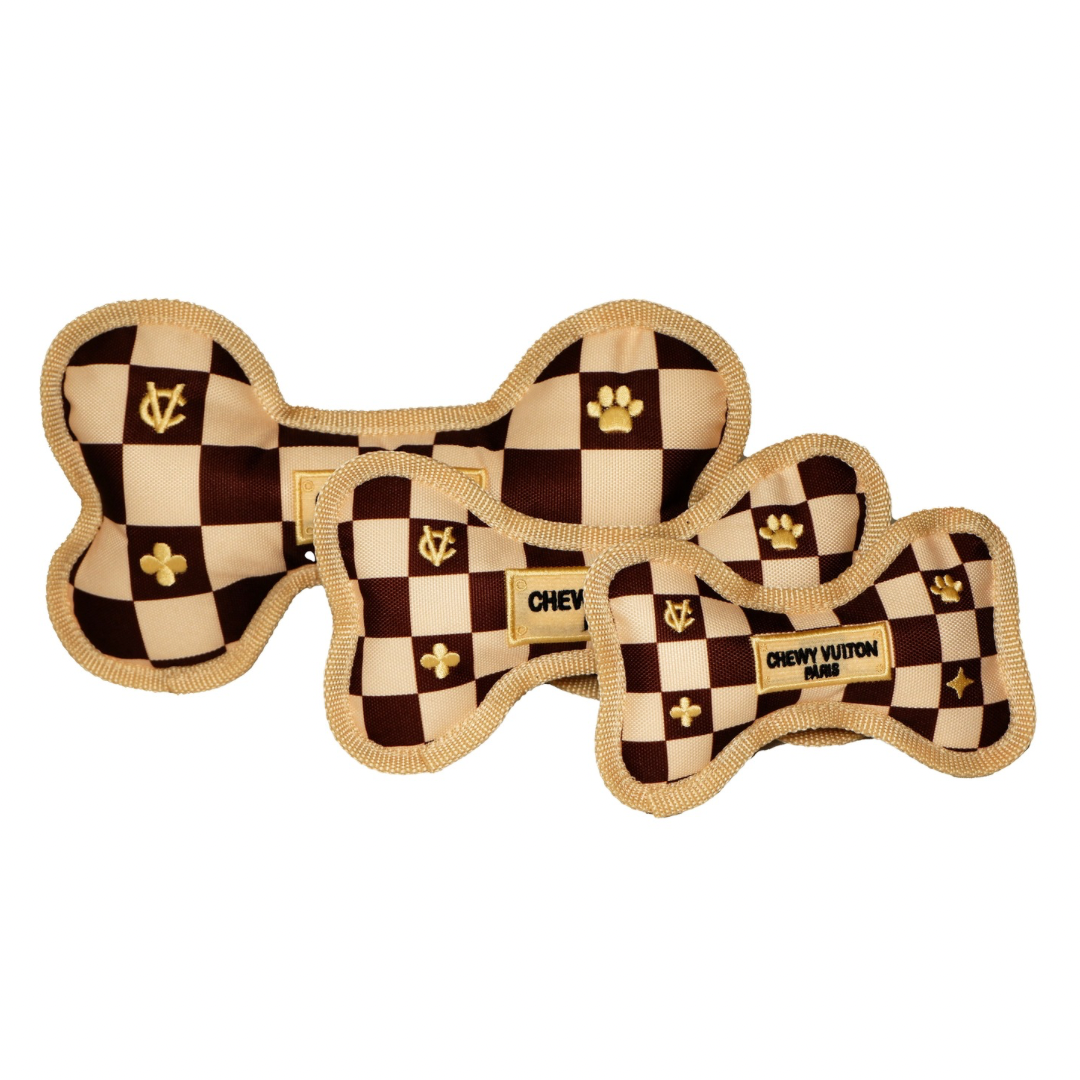 Set of three plush dog bone toys in brown check pattern with gold embroidery and “Chewy Vutton Paris” label. Luxury squeaky chew toys for pets.