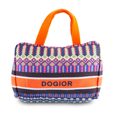 Plush dog toy shaped like a handbag with colorful geometric pattern, orange handles, and “Dogior” embroidered on the front. Soft designer-style squeaky chew toy for pets.