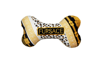 Plush dog bone toy with black, gold, and leopard print pattern featuring a gold embroidered “Fursace” label. Luxury designer-style squeaky chew toy for pets.