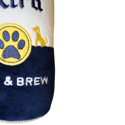 A soft plush dog toy designed like a beer can with the text “Grrrona Extra” and “Bark & Brew,” featuring a yellow paw print logo and dog silhouettes.