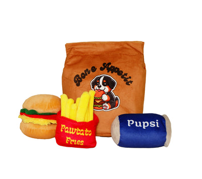 Lunch Box dog toy set featuring plush hamburger, pawtato fries, Pupsi drink, and a brown bag labeled “Bone Appetit”. Soft squeaky toys for pets.