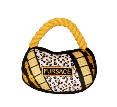 Plush luxury dog handbag toy with gold rope handle and black, leopard, and gold patterned design featuring a “Fursace” label. Designer-style squeaky chew toy for pets.