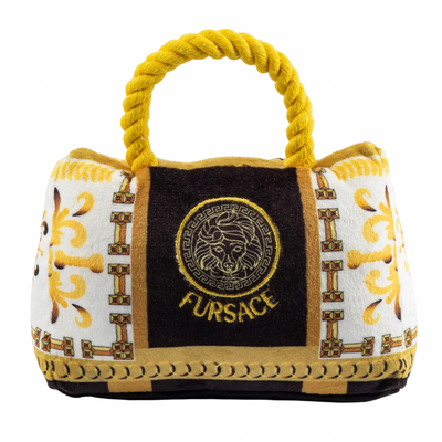 Plush dog toy designed like a luxury handbag with a gold rope handle, ornate white and gold baroque patterns, and an embroidered “Fursace” logo on the front.