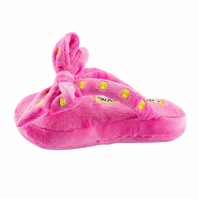 Plush dog toy shaped like a pink designer sandal with a large bow, gold stud details, and “Wagentino” embroidered on the footbed.