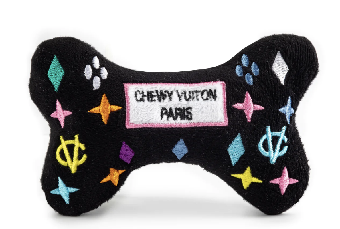 Black plush dog bone toy with colorful embroidered designer-style icons and a “Chewy Vuiton Paris” label. Soft luxury squeaky chew toy for pets.