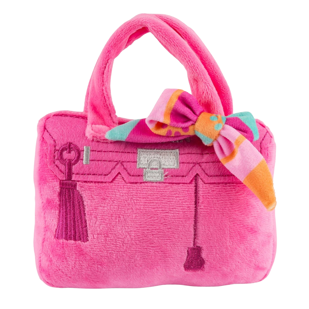 Plush dog toy shaped like a handbag with soft handles and embroidered text “Rich Bitch” on the front. Available in pink and orange colors. Luxury squeaky chew toy for pets.