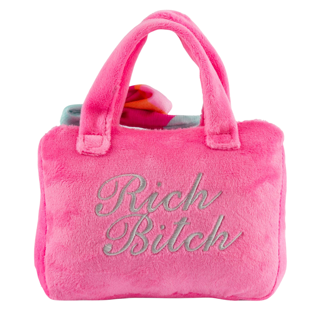 Plush dog toy shaped like a handbag with soft handles and embroidered text “Rich Bitch” on the front. Available in pink and orange colors. Luxury squeaky chew toy for pets.