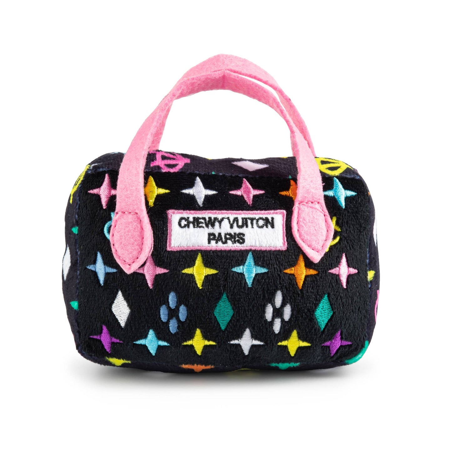 Plush dog toy shaped like a designer handbag with a black base, colorful embroidered icons, and pink handles featuring a “Chewy Vuiton Paris” label. Luxury squeaky chew toy for pets.