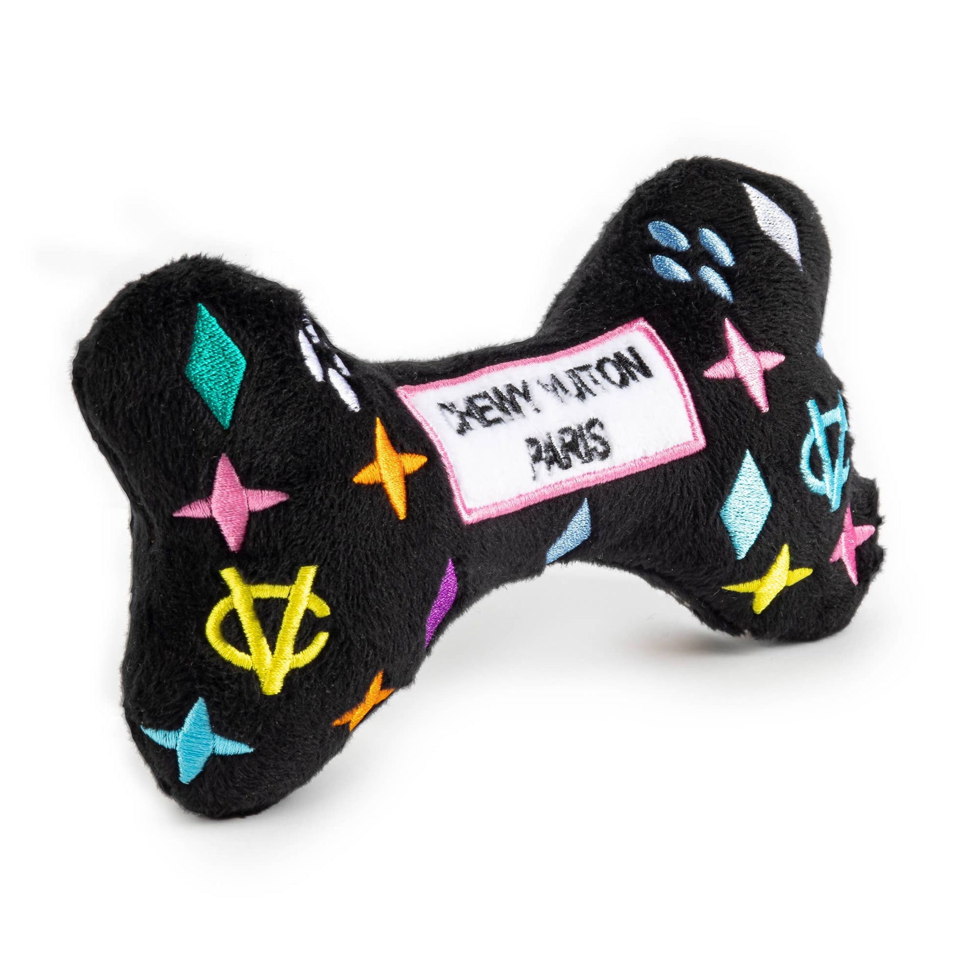 Black plush dog bone toy with colorful embroidered designer-style icons and a “Chewy Vuiton Paris” label. Soft luxury squeaky chew toy for pets.
