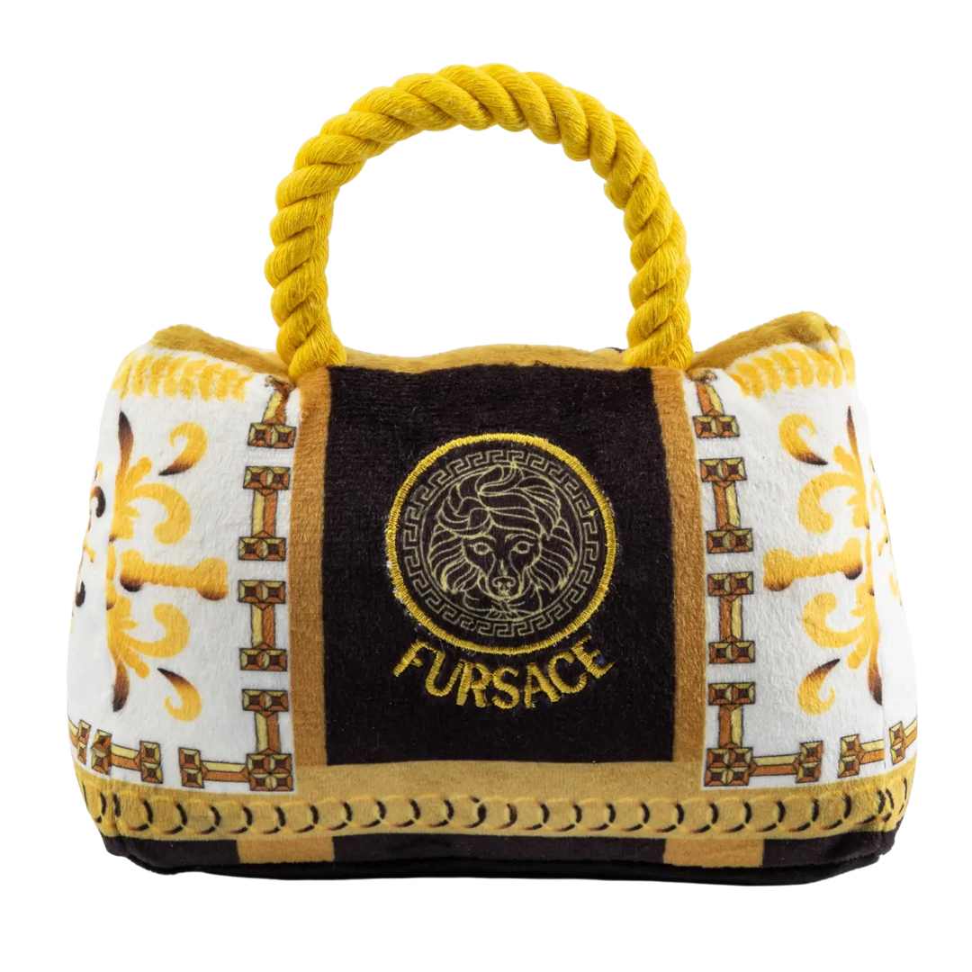 Plush dog toy designed like a luxury handbag with a gold rope handle, ornate white and gold baroque patterns, and an embroidered “Fursace” logo on the front.