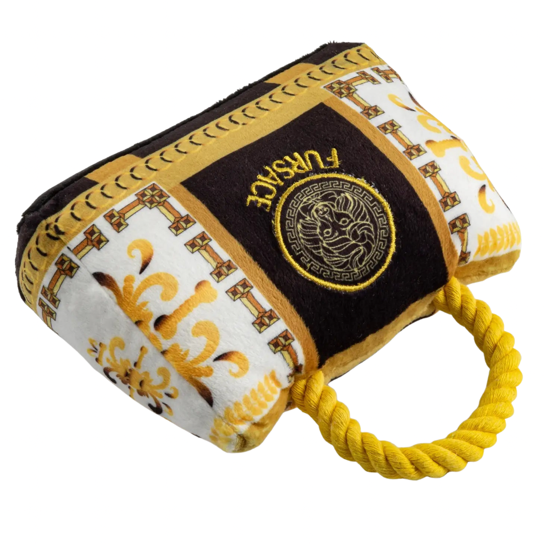Plush dog toy designed like a luxury handbag with a gold rope handle, ornate white and gold baroque patterns, and an embroidered “Fursace” logo on the front.